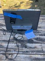 Front view of gray Sony radio with remote taped to front and small note indicating iPhone compatibility, showing control panel and speaker grille.