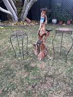 View of all three plant stands outdoors on grass, showing two metal stands flanking the wooden multi-platform stand in the center.