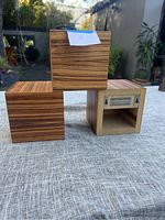 Three wooden cube shelve units stacked on a textured cloth surface, showing wood-grain exterior finish and neutral interior.