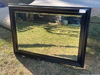 Full view of the Z Gallery wood framed beveled mirror outdoors showing frame and glass condition.