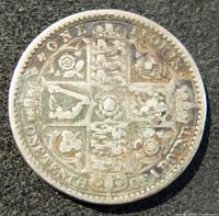 Photo showing the reverse side of the coin with detailed shield and inscriptions indicating 'ONE FLORIN' and floral and harp symbols.