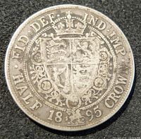 Reverse of the 1895 silver half crown displaying a crowned shield with intricate floral patterns, inscriptions including 'FID DEF IND IMP HALF 1895 CROWN'.