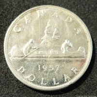 Reverse side of 1957 Silver Canada Dollar featuring two paddlers in a canoe with date and denomination.