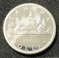 Obverse side of the 1965 Canada silver dollar coin showing two people in a canoe with northern lights background and the year 1965.