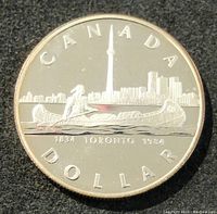 Obverse side of the coin showing Toronto skyline, CN Tower, paddling figure in canoe, and inscriptions 'CANADA', 'DOLLAR', '1834 TORONTO 1984'