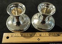 Pair of silver candle holders viewed from top, showing round, flared design and polished silver surface.