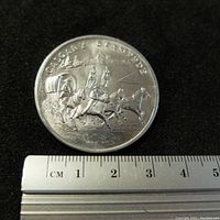 Close-up of the obverse side showing detailed engraving of Calgary Stampede scene with covered wagon, horses, and riders, with measurement scale showing about 3.5 cm diameter.