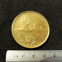 Top side of the medallion showing The Big Nickel monument, Sudbury cityscape, and inscriptions.