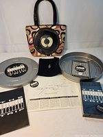 Full lot showing cloth purse with embedded 45rpm record and the Magical Mystery Tour Silver Edition set with VHS, map, booklet, and metal reel container