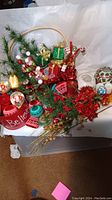 Overview of Christmas decorative basket with faux greenery, wrapped gifts, satin ornaments, and floral picks
