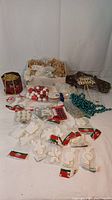 Wide view of various Christmas crafting supplies including ceramic ornaments, beads in multiple colors, packaged red and white ornaments, and fabric bolts.
