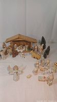 Photo showing both nativity sets together with multiple figures including a wooden manger, several ceramic human and animal figures, and bottle brush trees.