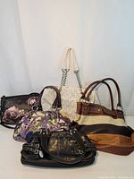 Photo of five assorted handbags and purses of various styles and colors.