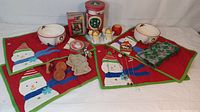 Overview of the kitchenware lot showing snowman placemats, bowls, ornaments, cookie cutters, and glass items