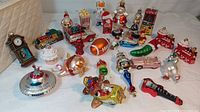 Photo showing an assortment of over 20 mercury glass ornaments including clock, pig, spaceship, cupcake, train, and other holiday-themed shapes.