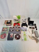 Full overview of all gaming consoles, controllers, game cases, discs, and accessories laid out on a white surface