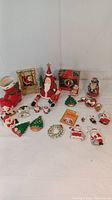 Full view of all the assorted Christmas and Santa-themed decorative ornaments laid out, showing variety of Santas, Christmas trees, wreaths, and bells in red, green, white colors.