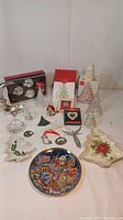 Overview of assorted vintage Christmas items including glass votive candle holders shaped like trees, metal angel ornaments, wax tree candle, star-shaped plates, and a Pepsi collector plate