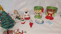 Lot contents showing candle holders, choir and angel figurines, handmade ornaments, and ceramic Christmas tree
