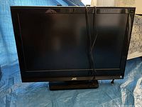 Front view of the JVC 32-inch TV showing black display and frame with stand.