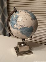 Front view of half-size table globe showing North and South America with metallic stand and base