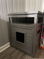 Front view showing square entrance for cat and wooden horizontal slats constructing the enclosure.