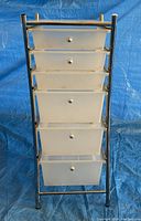 Front angle view of the full plastic drawer unit showing five drawers and metal frame with a blue backdrop.