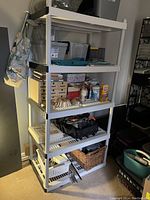 Full view of the white plastic shelving unit filled with various household and storage items, showing all five shelves clearly.