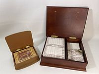 Two wooden boxes of stationary sets displayed with lids open. Larger box to right containing vintage map and nautical design stationary sheets and smaller notepad secured with cord. Smaller box to left showing tiger illustration stationary sheets inside.