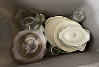 Clear depression glass bowls, white ceramic serving dishes including a lidded casserole dish, and clear glass mason jars in a bin.