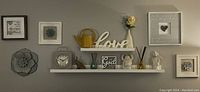 Full view of wall decor including the two floating shelves with various decorative items, framed quotes, and a large metal flower wall sculpture.