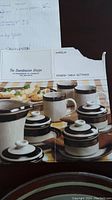Photo of a vintage Finnish table setting brochure featuring Karelia Arabia dinnerware with brown and beige bands and lids on jars.