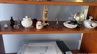 Overall shelf display with multiple rabbit figurines, decorative dishes, cartoon rabbit face figurine, a small round alarm clock, and a candy holder shaped like a dog.