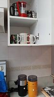 Cupboard shelf with nine coffee mugs and two Bodum coffee presses