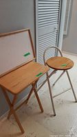 Three items: wooden bed tray with white top, wooden TV tray, and wooden seat stool with metal legs and foot rest