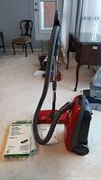 Full view of vacuum cleaner, wand, hose, manual and bag sets on carpet