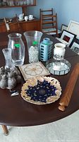 Photo showing various vases, decorative plate, mirrored tray, trivet, wooden wall hanging sculpture, and small sculpture on a table.