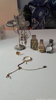 Lot showing three wrist watches, assorted jewelry including bracelet and stud earring, and a cat-shaped jewelry stand holding dream catcher earrings.