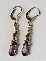 Front view of both earrings showing pear-shaped faceted amethyst and gold bead cluster dangles with leverback closures