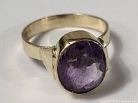 Front angle showing bezel-set oval amethyst and gold band