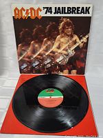 Photo showing the vinyl record partially out of its sleeve, front cover shows guitarist on stage with motion effect.