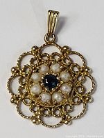 Front view of antique gold filigree pendant showing sapphire central stone and surrounding pearls