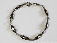 Top view of sterling silver marquisette bracelet with gold buttons on each link, closed in a circular shape.