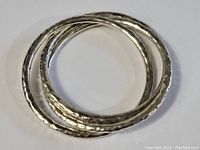 Top view of three intertwined hammered sterling silver bangle bracelets showing overall design and finish.