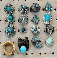 Display of 16 vintage turquoise rings in various silver-tone settings, mostly adjustable except one size 2 ring. Many with ornate metal designs and cluster turquoise stones.