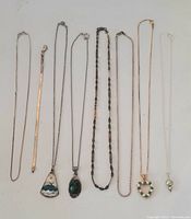Group view of 8 sterling silver jewelry pieces consisting of various necklaces and bracelets, some with colorful inlaid pendants.