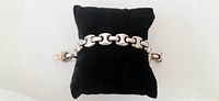 Sterling silver chain link bracelet displayed on a black cushion.