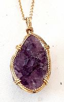 Close-up of natural amethyst pendant showing raw crystal facets and gold-tone wire wrap setting