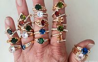 Front view of all rings worn on fingers showing variety of colored stones and rhinestone accents
