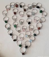 Top view of the full group of 34 rings laid out in a triangle shape showing various colored stones and band designs